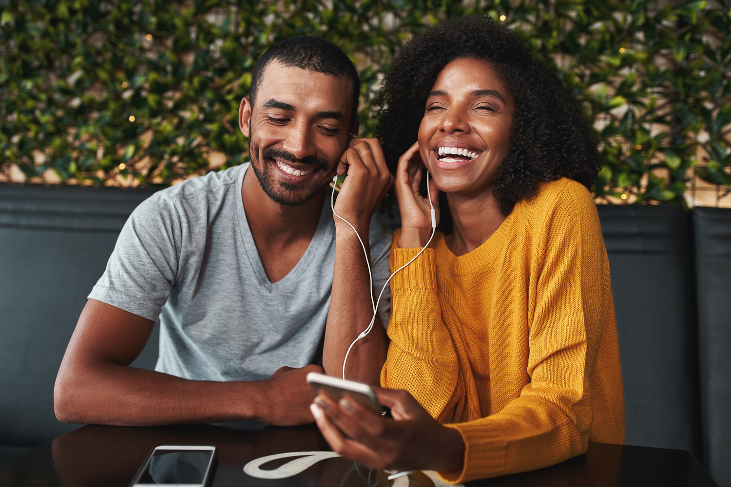 Una pareja escucha música de un smartphone con unos auriculares de botón